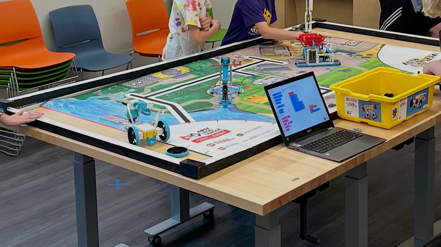 A FIRST LEGO League challenge table with a robot and a laptop running block code